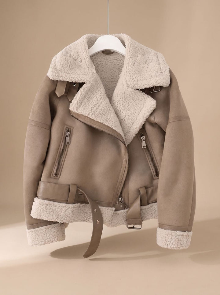 Mujer luciendo chaqueta aviador asimétrica de borreguito sintético. Moda de invierno con cinturón.