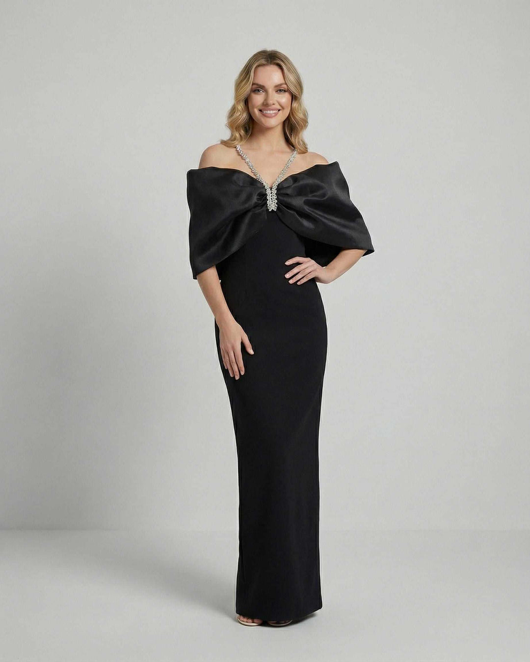 Vestido elegante de mujer color celeste, corte maxi, con hombros descubiertos y lazo dramático. Fiesta y noche.