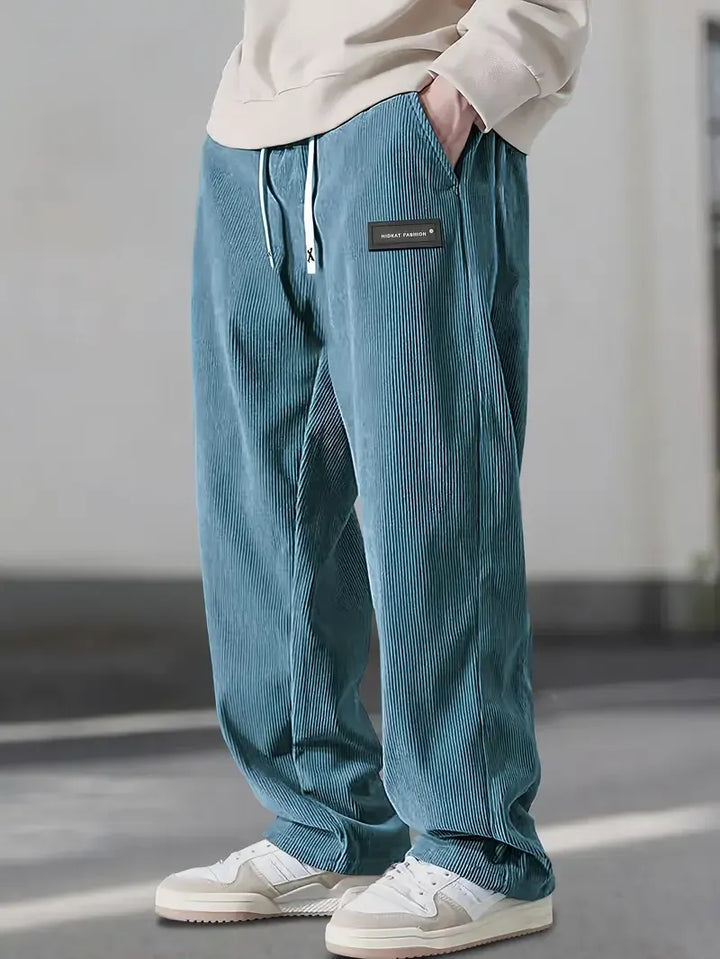 Cintura y botón de pantalones de pana de hombre, diseño robusto que asegura comodidad.