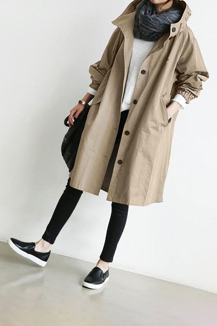 Mujer luciendo trench impermeable con cinturón y capucha, combinando estilo femenino y funcionalidad.