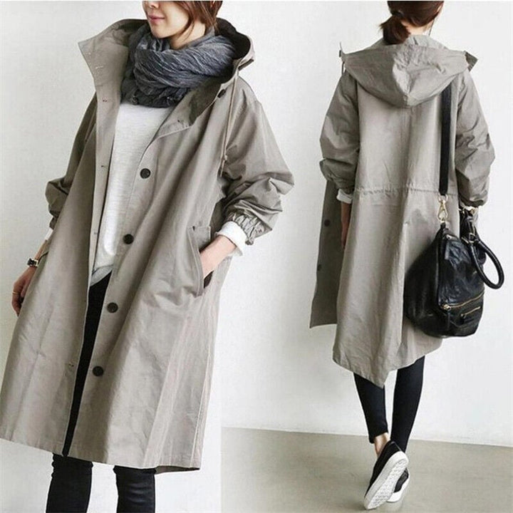 Detalle de trench impermeable de mujer con capucha, cinturón ajustable y tejido de alta calidad para lluvia.
