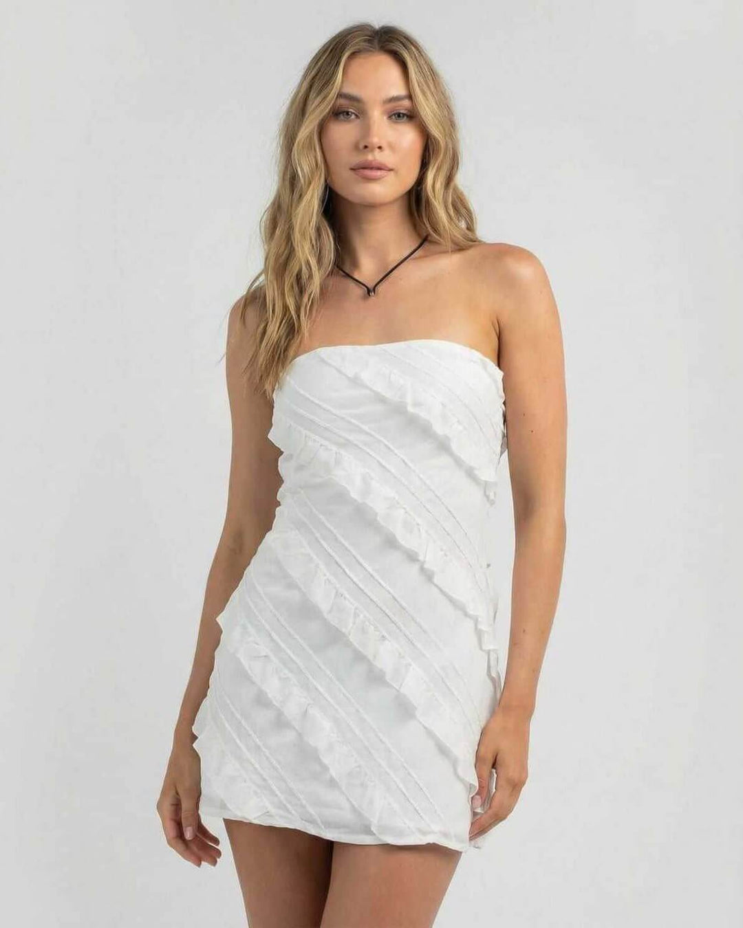 Vestido mini de fiesta blanco con volantes, estilo tubo sin tirantes. Moda joven elegante para ocasión especial de verano.