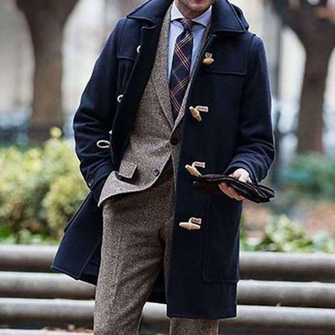 Abrigo largo clásico con capucha para hombre, ideal para invierno. Diseño elegante con botones toggle, disponible en azul marino.
