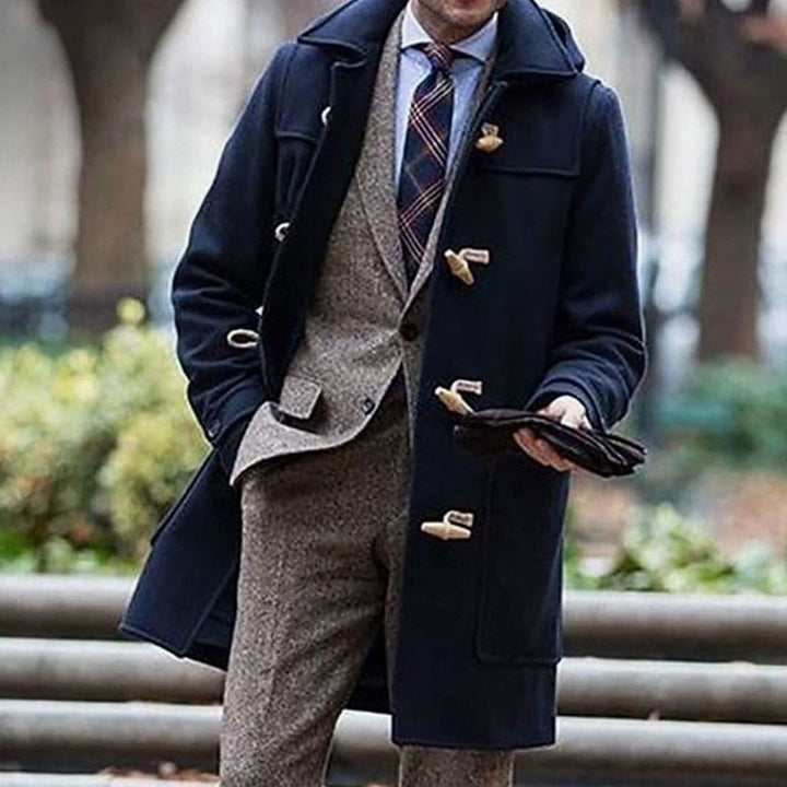 Abrigo largo clásico con capucha para hombre, ideal para invierno. Diseño elegante con botones toggle, disponible en azul marino.