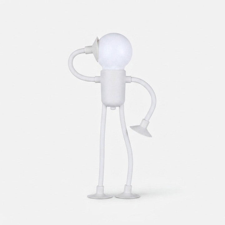 Lámpara de mesa LED con figura humana articulada, emite luz cálida, ideal para lectura o ambiente.