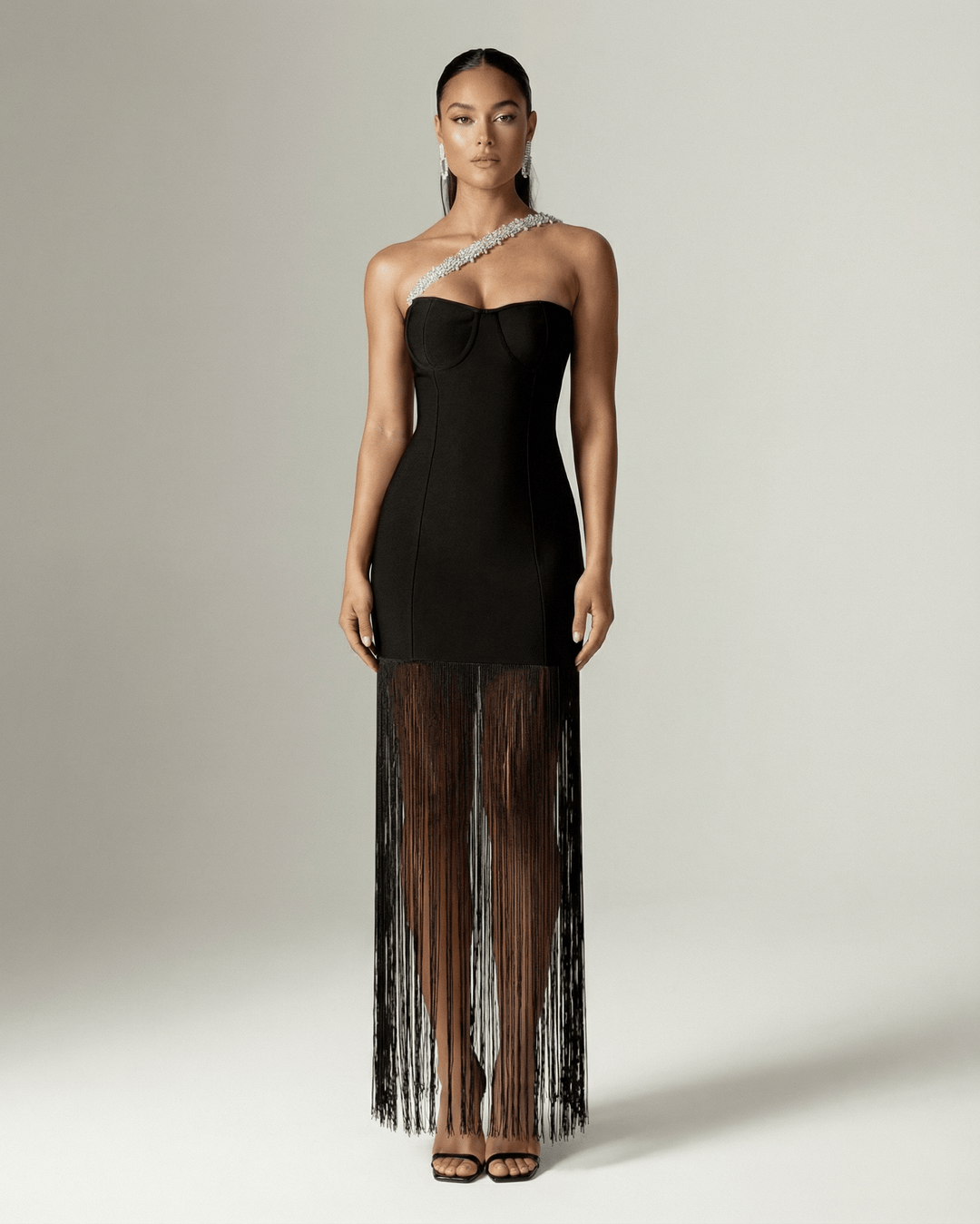 Detalle del diseño de un hombro y los flecos en un vestido maxi negro elegante para mujer, ropa de noche.