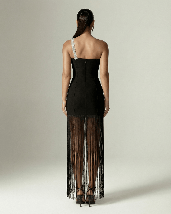 Mujer vistiendo vestido maxi negro de un hombro con flecos, moda femenina elegante perfecto para cóctel y gala.