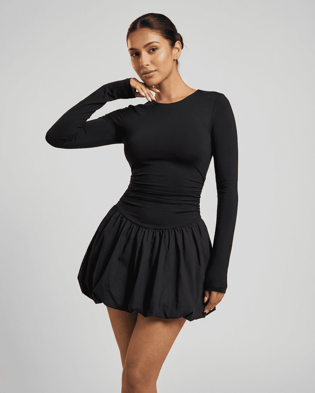 Vestido mini negro ajustado con volantes chic y manga larga para mujer. Elegancia moderna y favorecedora.