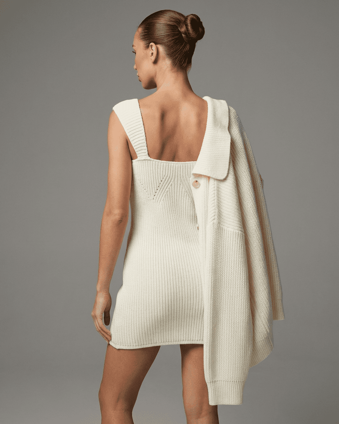 Elegante vestido mini blanco marfil sin mangas, con escote fuera del hombro. Moda femenina de fiesta.