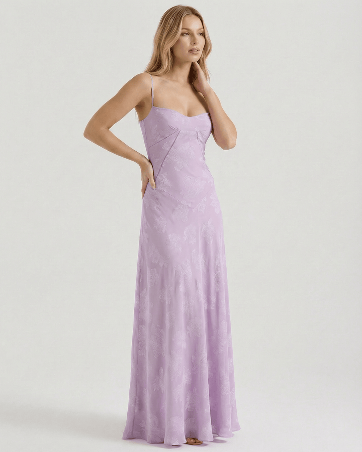 Mujer luciendo un romántico vestido maxi floral blanco con lazo en la espalda. Perfecto para bodas de día.
