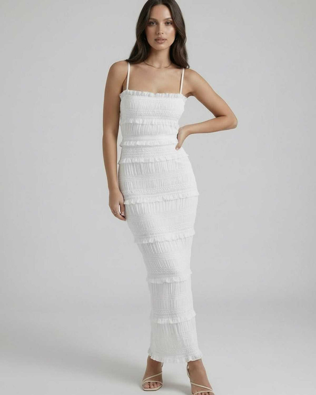 Mujer con vestido maxi blanco ceñido y tirantes finos. Ideal para fiestas de verano y silueta elegante.