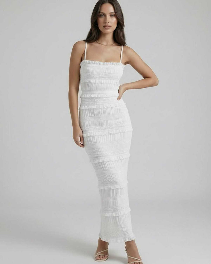 Mujer con vestido maxi blanco ceñido y tirantes finos. Ideal para fiestas de verano y silueta elegante.