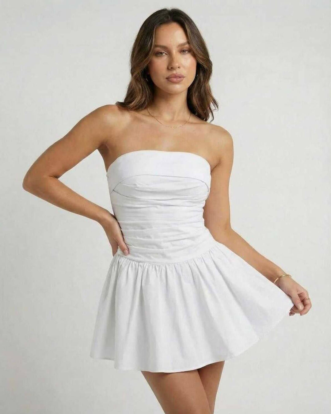 Look de verano con vestido mini blanco sin tirantes y silueta acampanada. Ropa fresca para días soleados.
