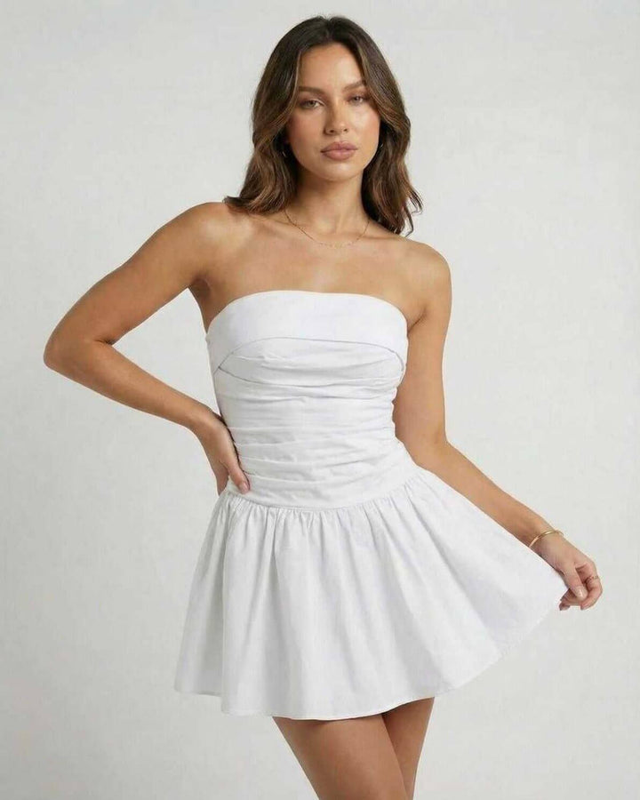 Look de verano con vestido mini blanco sin tirantes y silueta acampanada. Ropa fresca para días soleados.