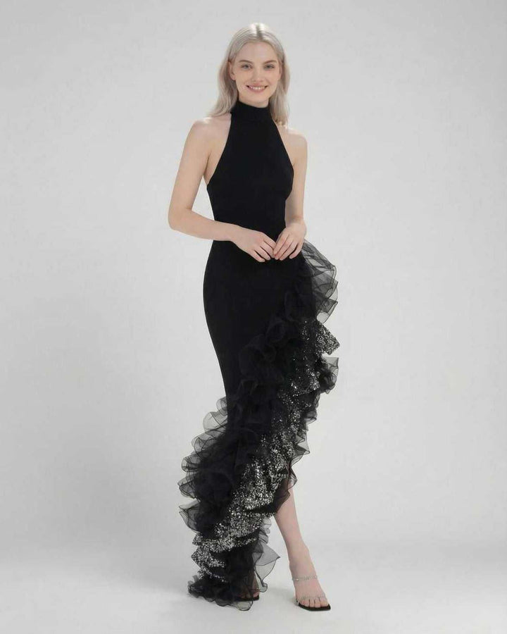 Mujer luciendo un vestido maxi negro de gala con cuello halter y corte asimétrico, ideal para bodas y fiestas.