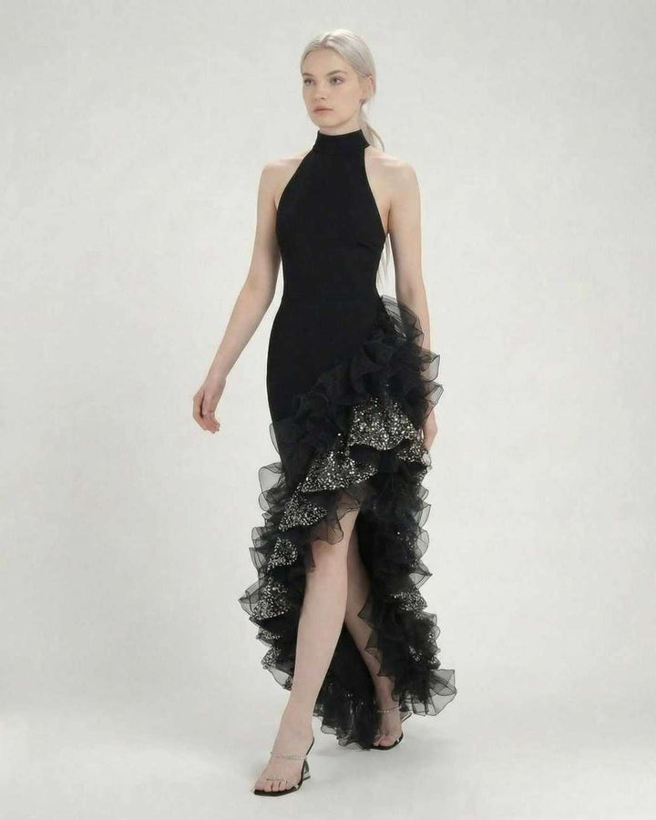 Atuendo de fiesta: mujer vistiendo un vestido maxi negro formal con cuello halter, volantes y diseño elegante.