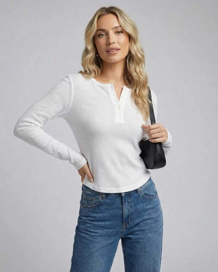 Espalda de top de manga larga blanco ajustado para mujer, destacando su corte moderno y silueta.