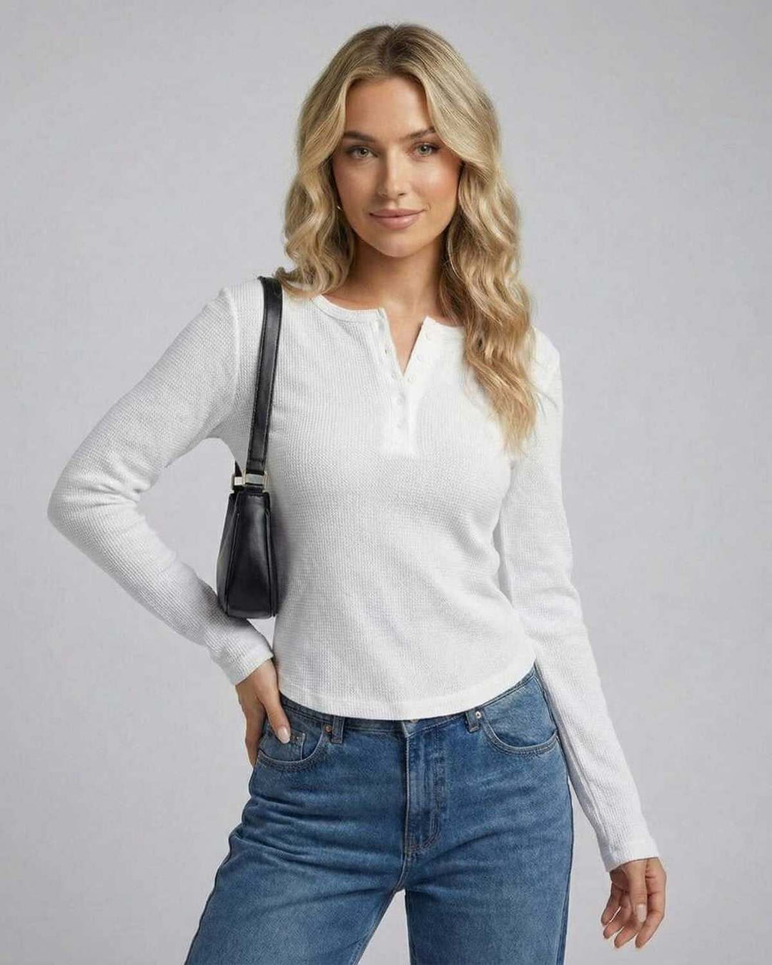 Mujer usando top blanco ajustado de manga larga, estilo básico y cómodo para el día a día.