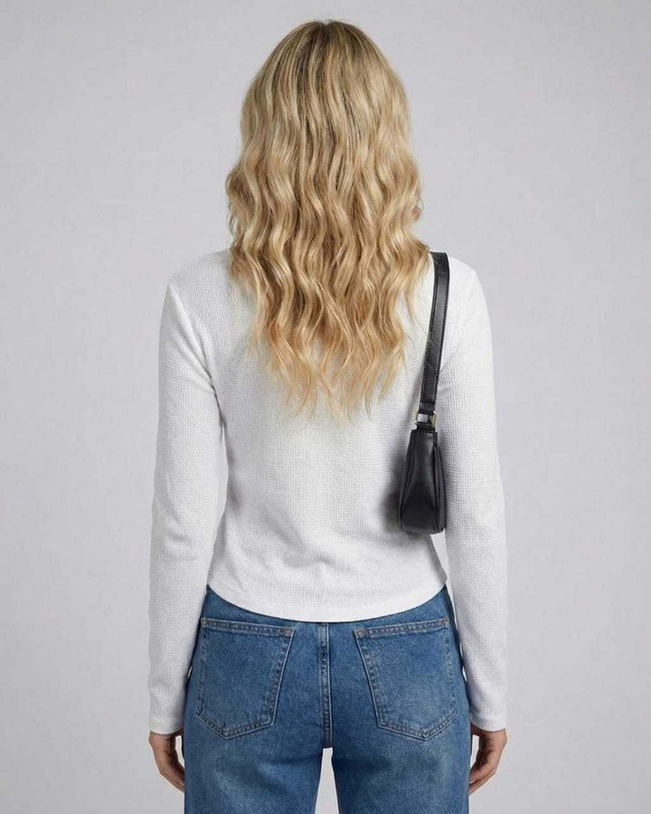 Primer plano de top ajustado de manga larga para mujer en tejido suave de poliéster y spandex.
