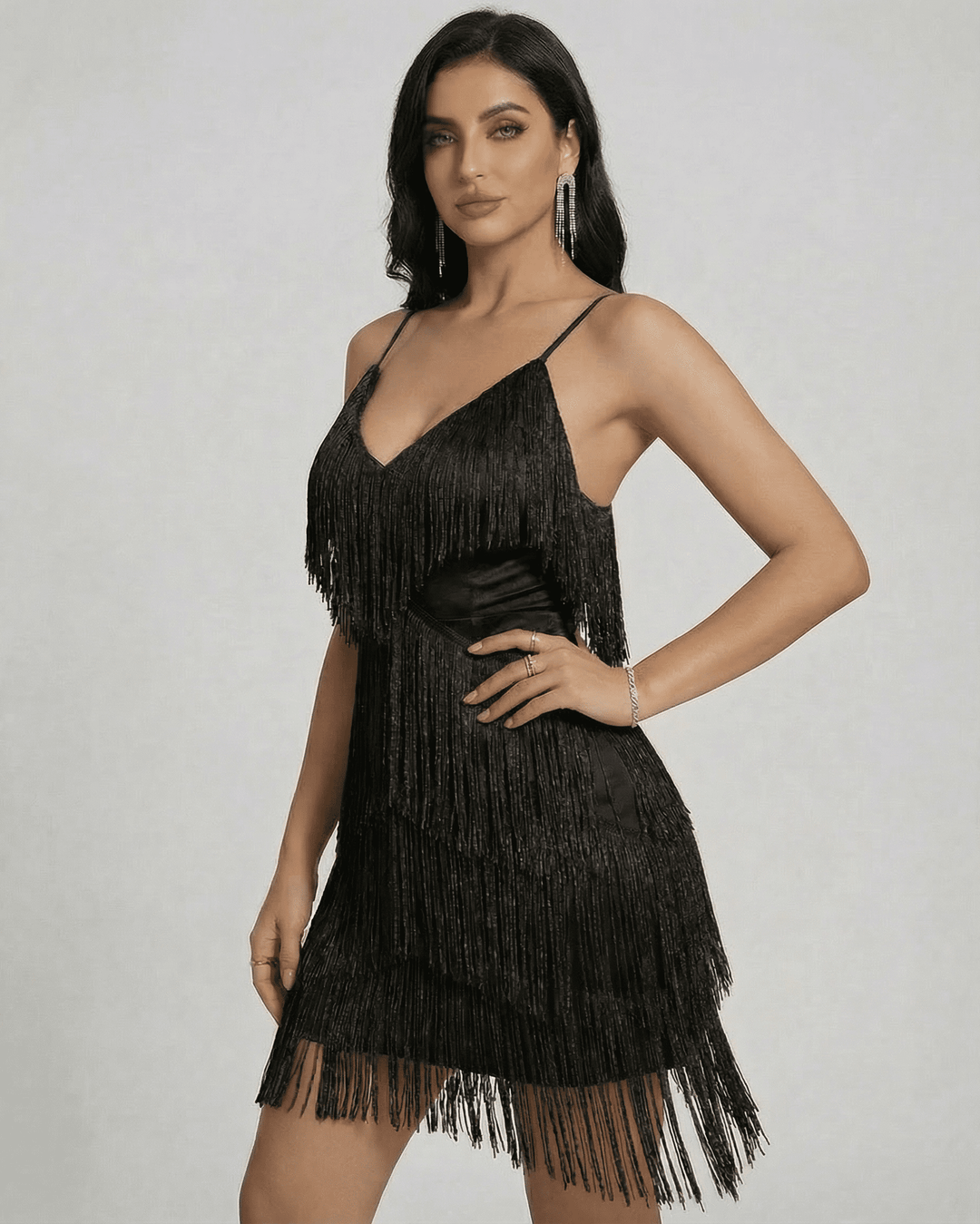 Modelo luciendo vestido mini negro de fiesta con flecos en movimiento y escote V. Silueta estilizada.