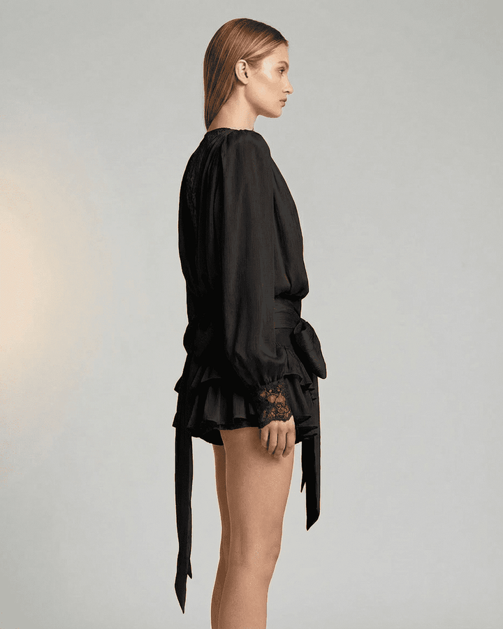 Vestido mini negro de mujer con volantes y encaje delicado, diseño elegante y manga larga. Versátil.