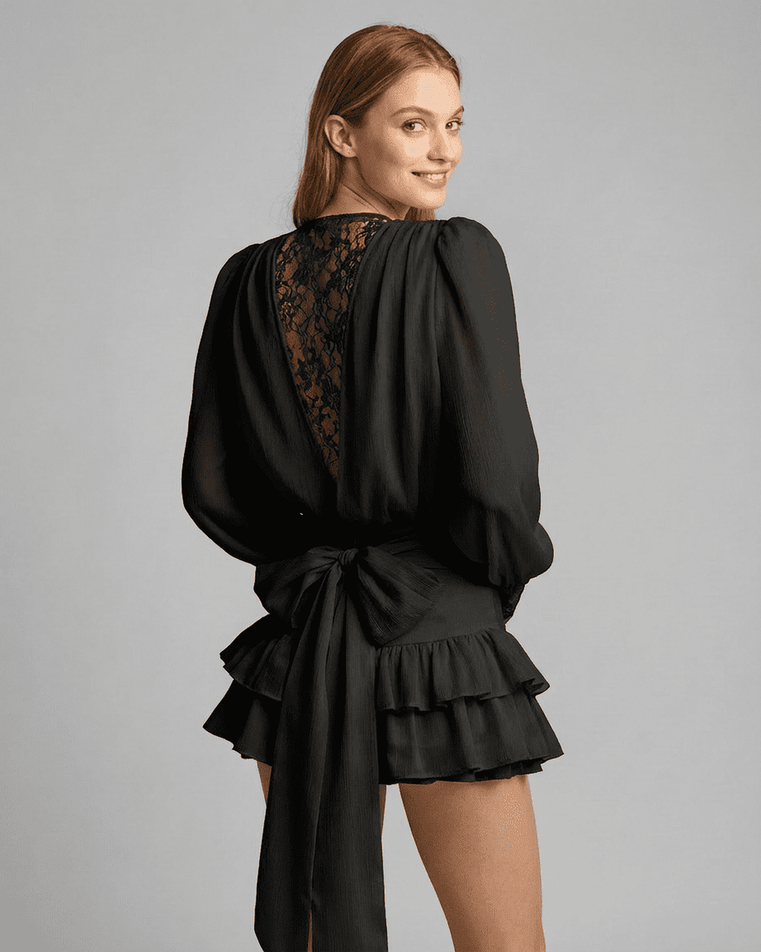 Mujer luciendo vestido mini negro elegante de manga larga con encaje, perfecto para cóctel o fiesta.