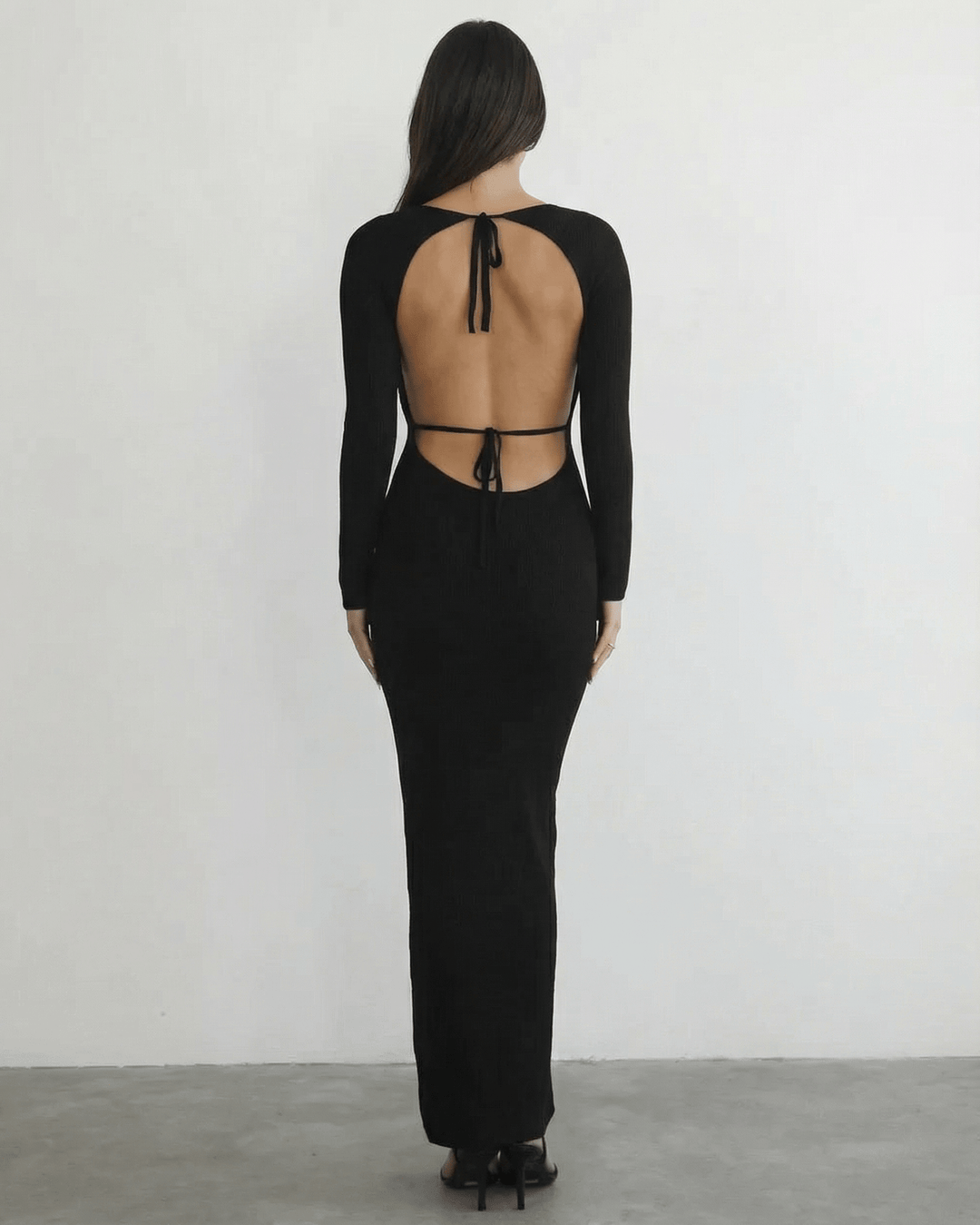 Vestido maxi negro estilizado con manga larga para mujer, detalle de espalda abierta.