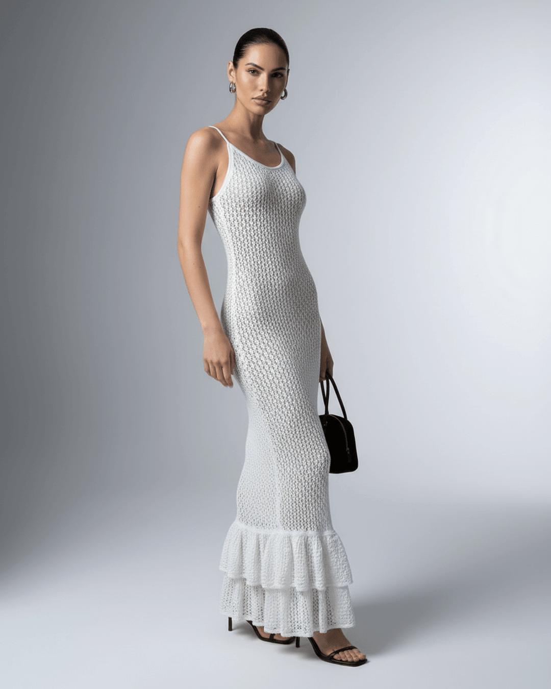 Silueta femenina en vestido maxi blanco perla ajustado, corte hueco. Look elegante y chic.