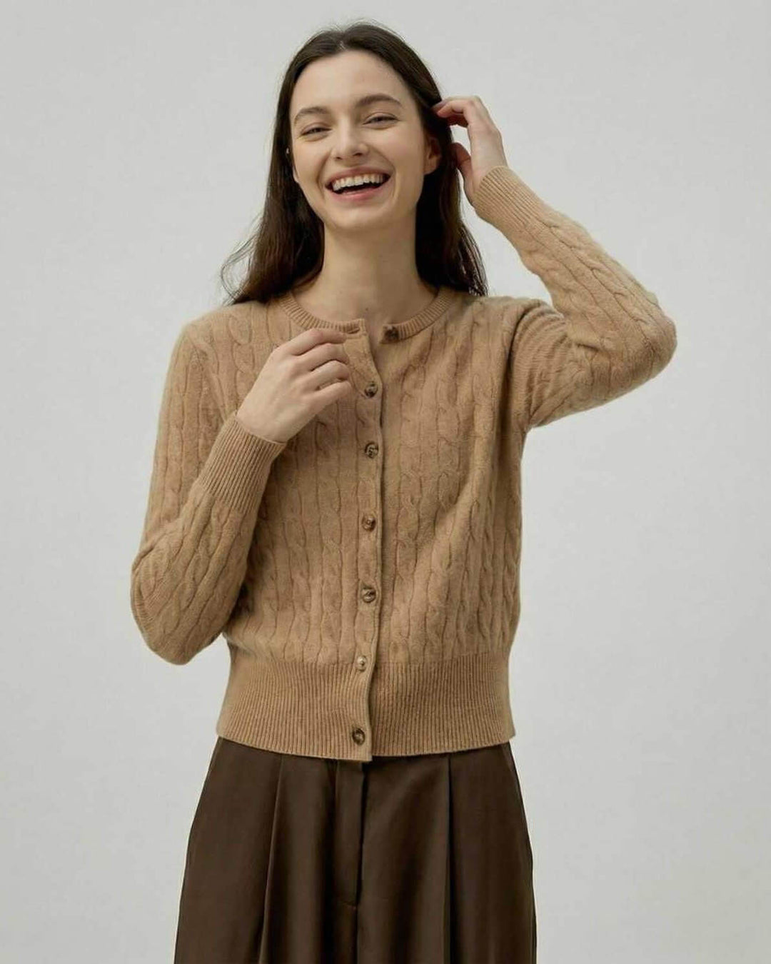 Mujer vistiendo cárdigan Sienna marrón trenzado. Suéter elegante de otoño/invierno que aporta versatilidad y calidez.