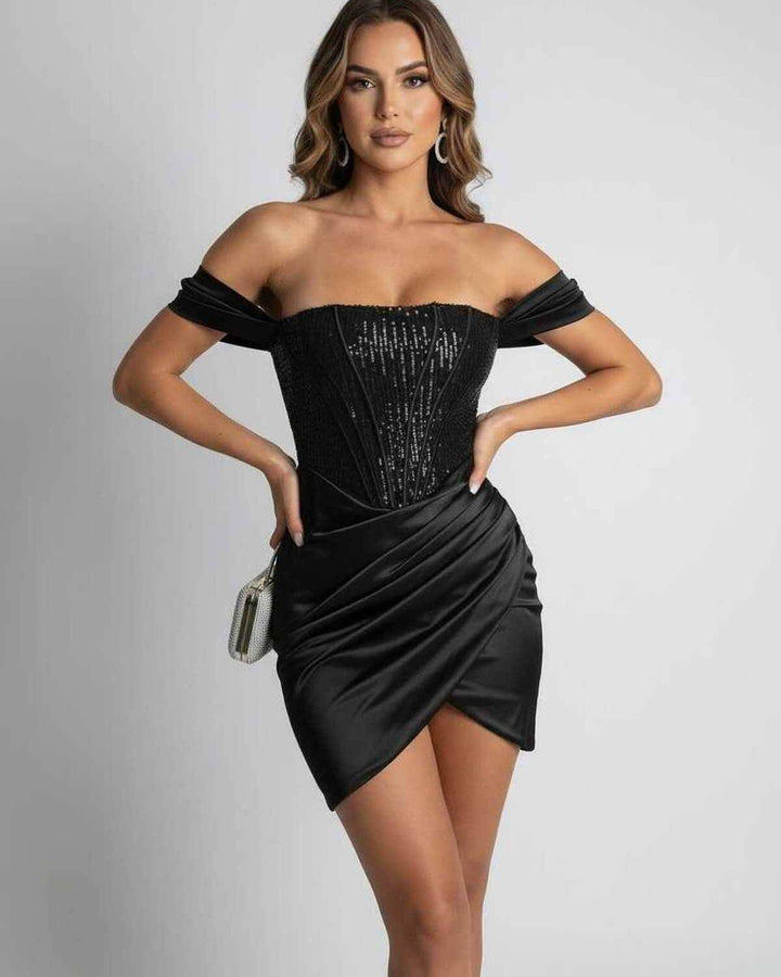 Vestido mini negro de fiesta con lentejuelas y hombros al descubierto, visto de espaldas. Destaca la silueta ajustada femenina.