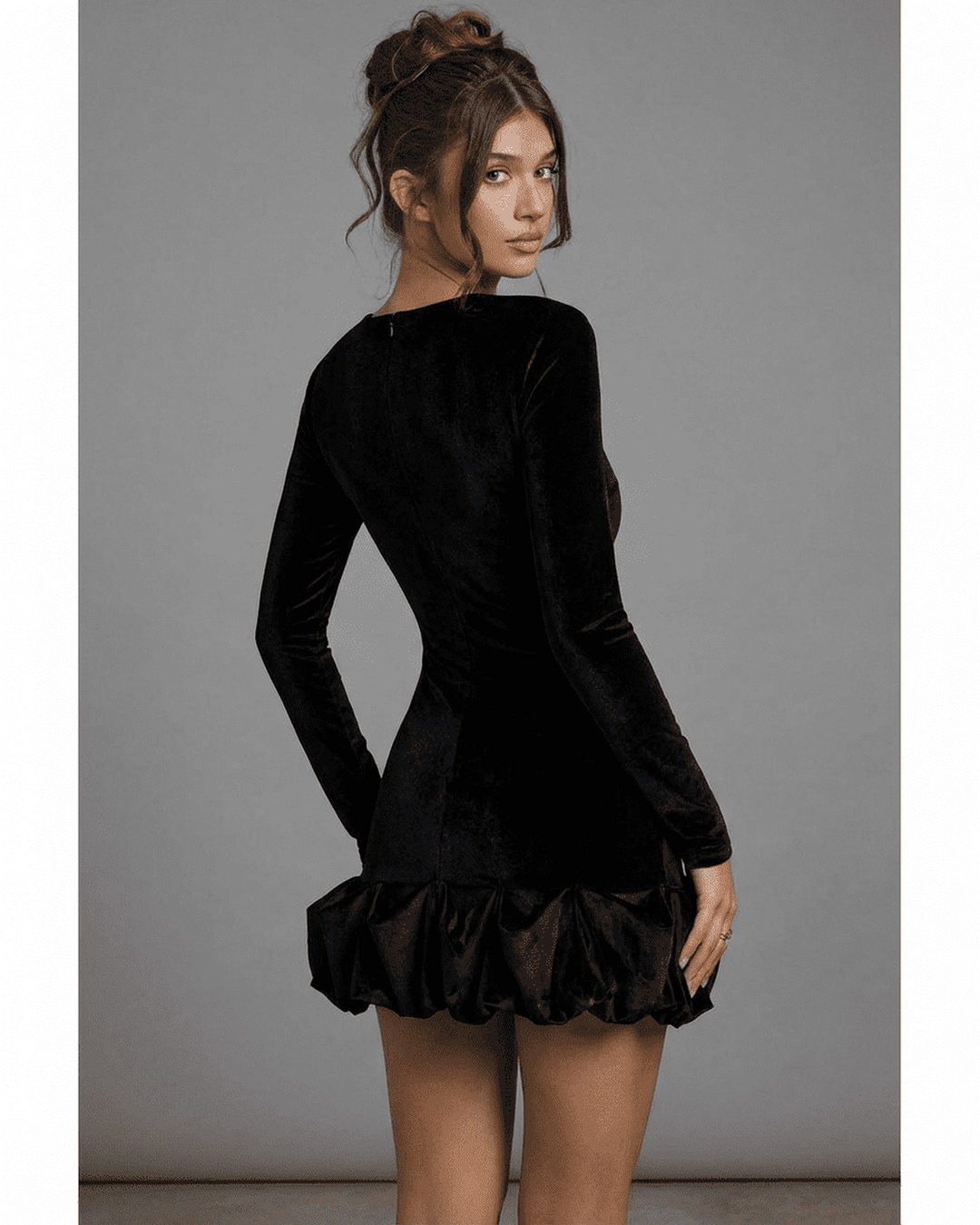 Modelo posando con sofisticado vestido mini negro Velora, perfecto para ocasiones especiales y moda femenina.