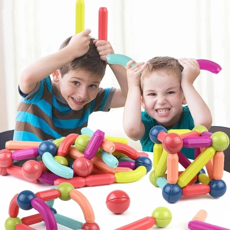 Niño jugando feliz con bloques magnéticos, construyendo una torre, fomenta aprendizaje divertido y habilidades motoras.