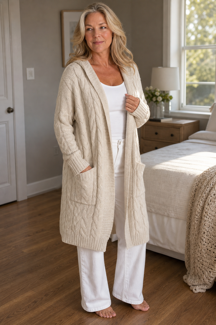 Mujer sonriendo con cárdigan de ochos y capucha, ropa cómoda y chic de otoño/invierno.