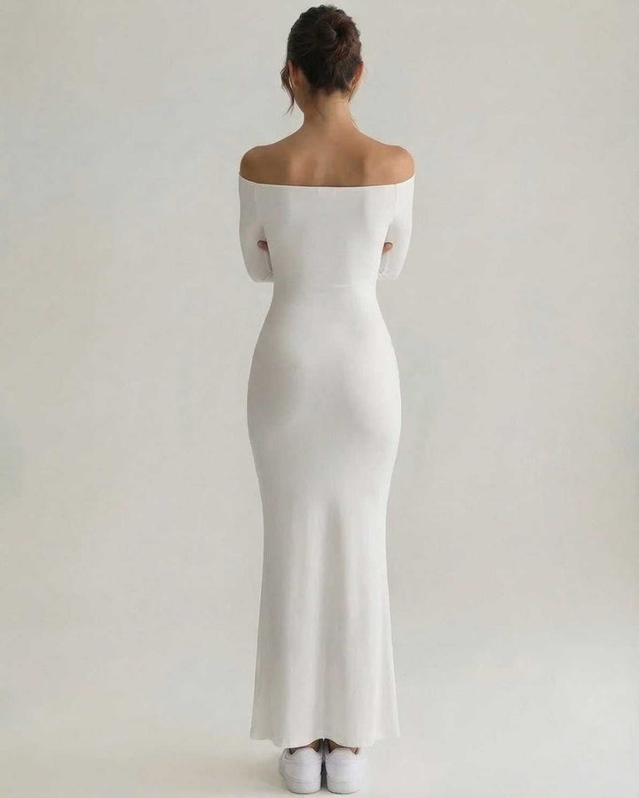 Vestido maxi blanco con escote asimétrico y manga larga, perfecto para cócteles y moda femenina sofisticada.