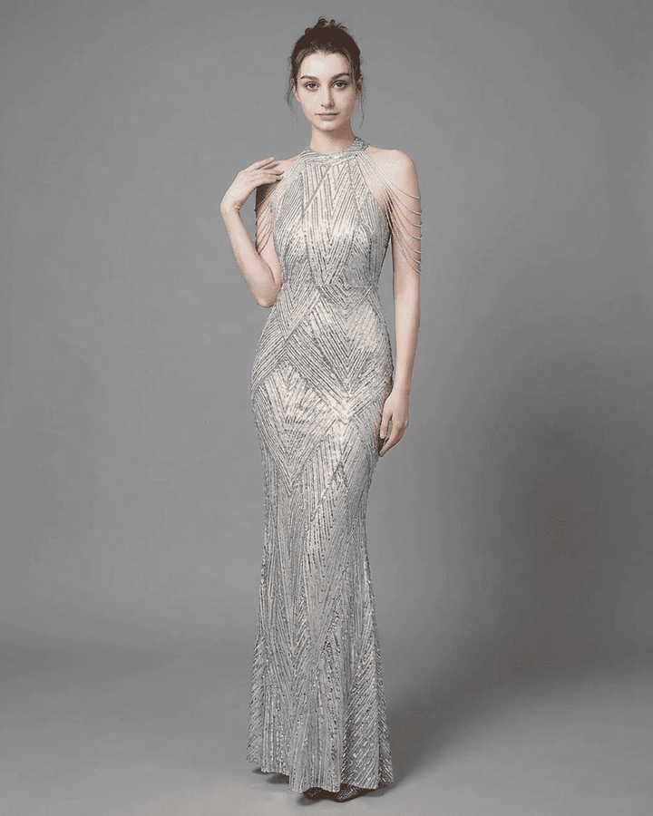 Vestido maxi de noche plateado con lentejuelas, estilo halter sirena, ideal para fiestas y galas elegantes.