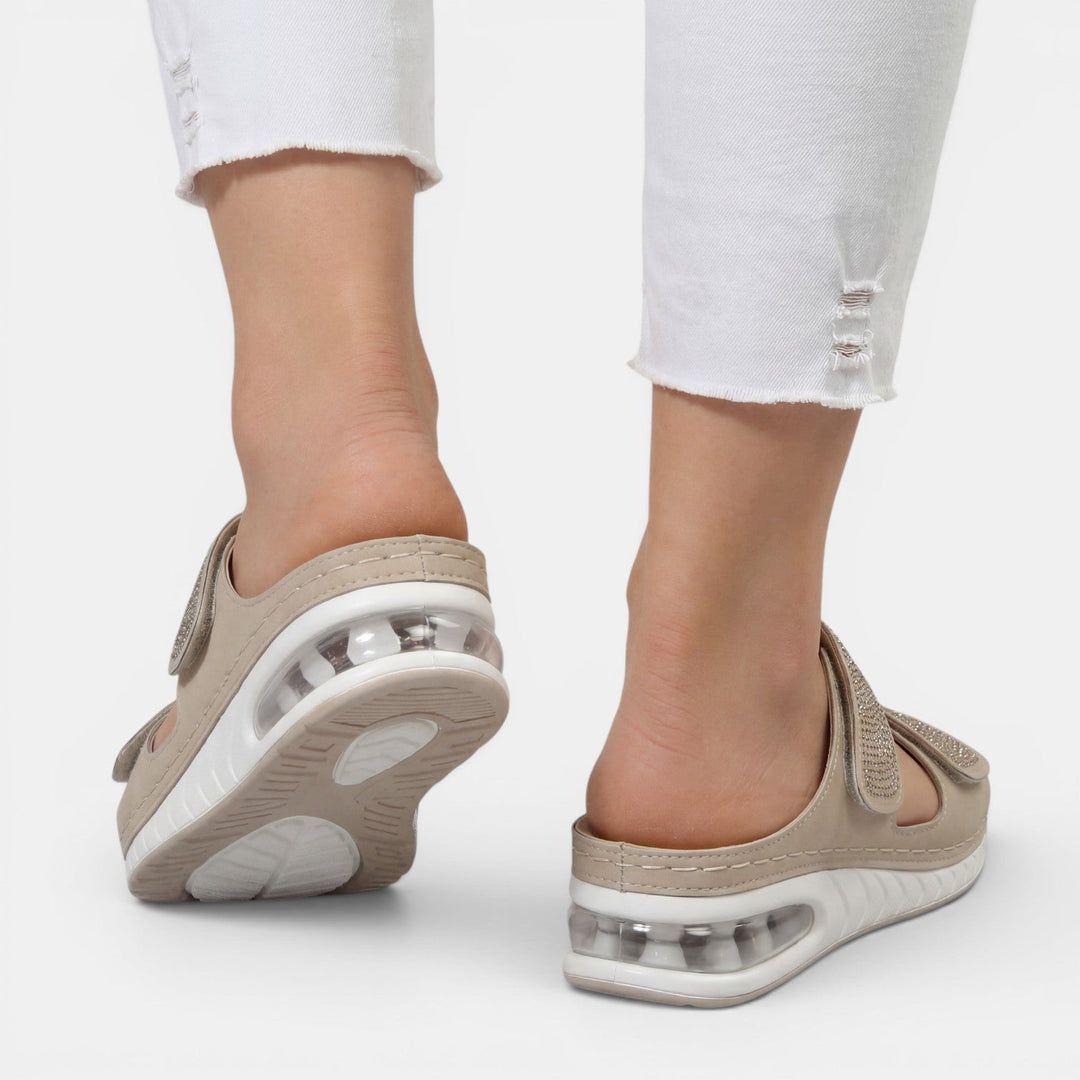 Primer plano de sandalias de mujer con cuña ergonómica y detalles de strass, para máximo confort.