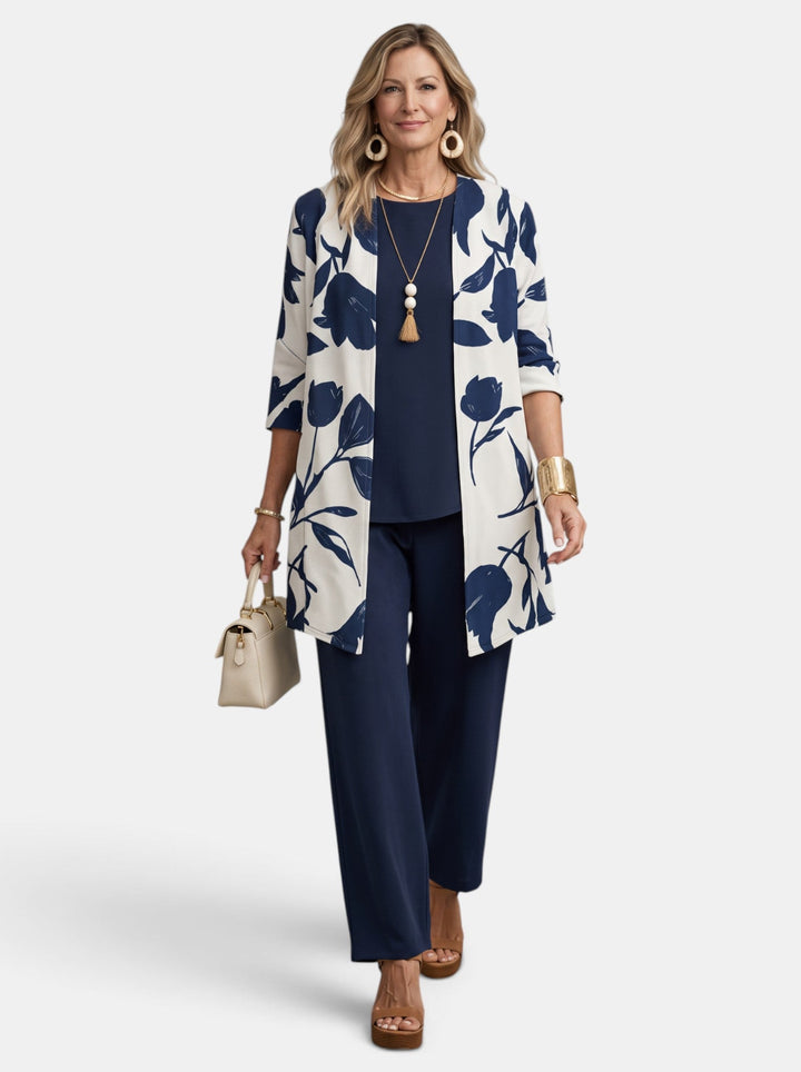 Mujer sonriente en conjunto de 3 piezas tropical. Look veraniego elegante y cómodo con blusa, pantalón y abrigo.
