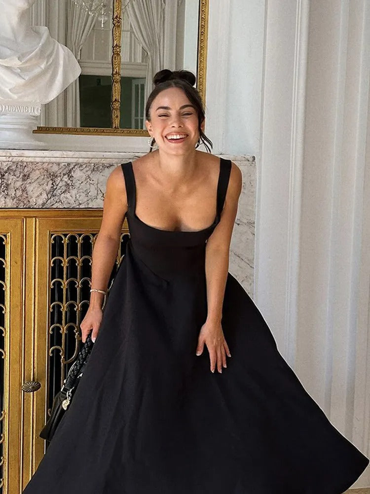 Mujer vistiendo vestido midi negro de corte elegante y favorecedor, ideal para fiesta o cóctel.