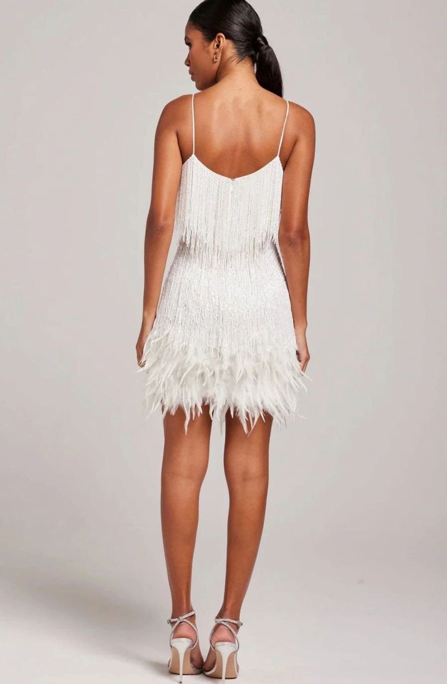 Mujer luciendo vestido corto de fiesta con flecos, pedrería y plumas. Noche de glamour.