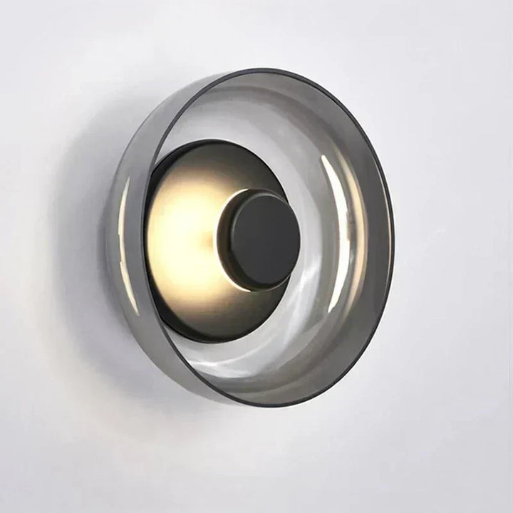 Aplique de pared Aurelia con cristal ahumado; iluminación moderna y minimalista que crea un ambiente suave.
