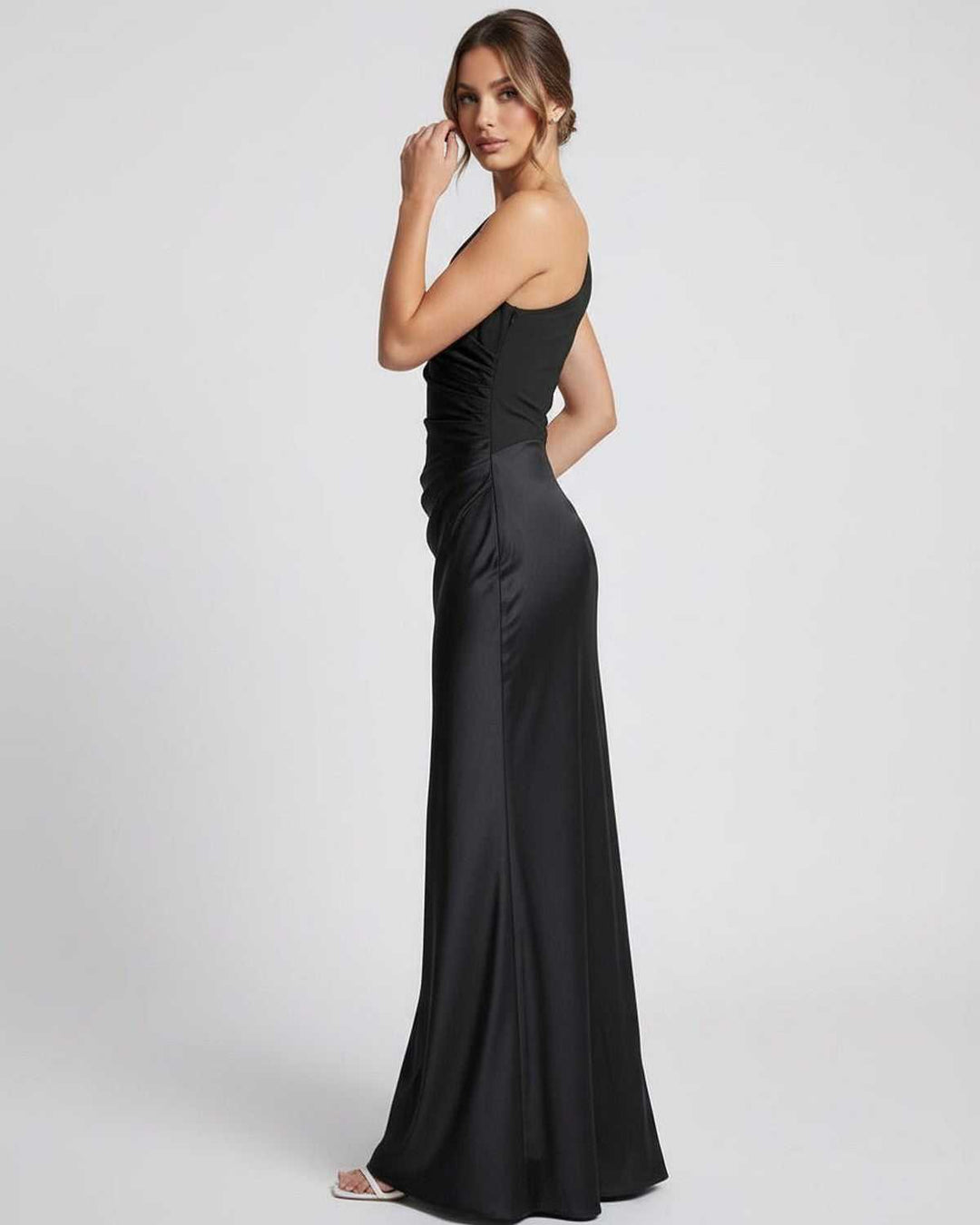 Modelo posando con vestido maxi negro formal de un hombro. Ideal para ocasiones especiales y cenas.