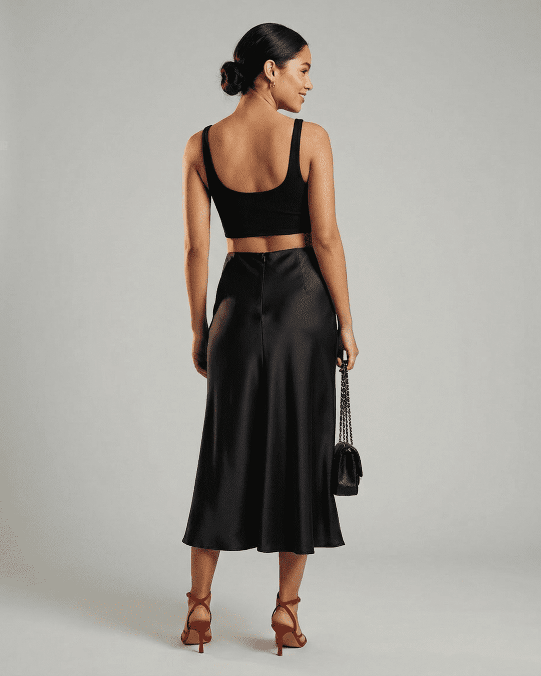 Modelo luciendo falda midi negra sirena, look elegante de noche. Moda femenina clásica para eventos.