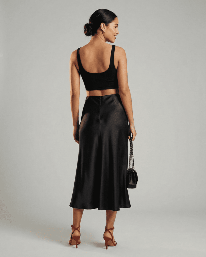 Modelo luciendo falda midi negra sirena, look elegante de noche. Moda femenina clásica para eventos.