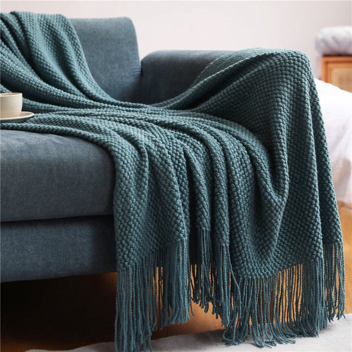 Manta nórdica tejida gris sobre sofá, estilo escandinavo, confort para sala y hogar.