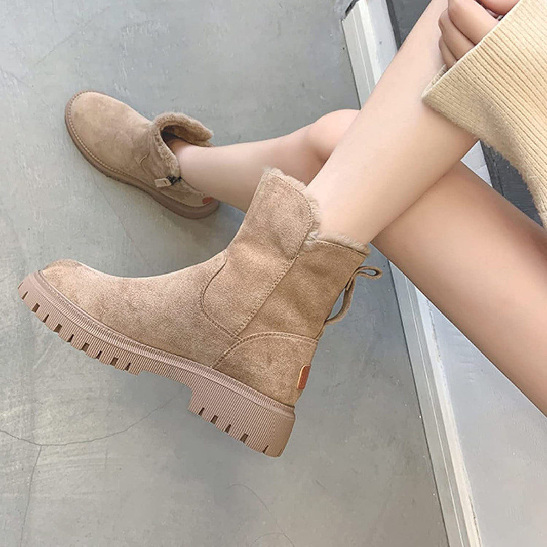 Botas de invierno para mujer en un paisaje nevado, resaltando su diseño impermeable y protección térmica.