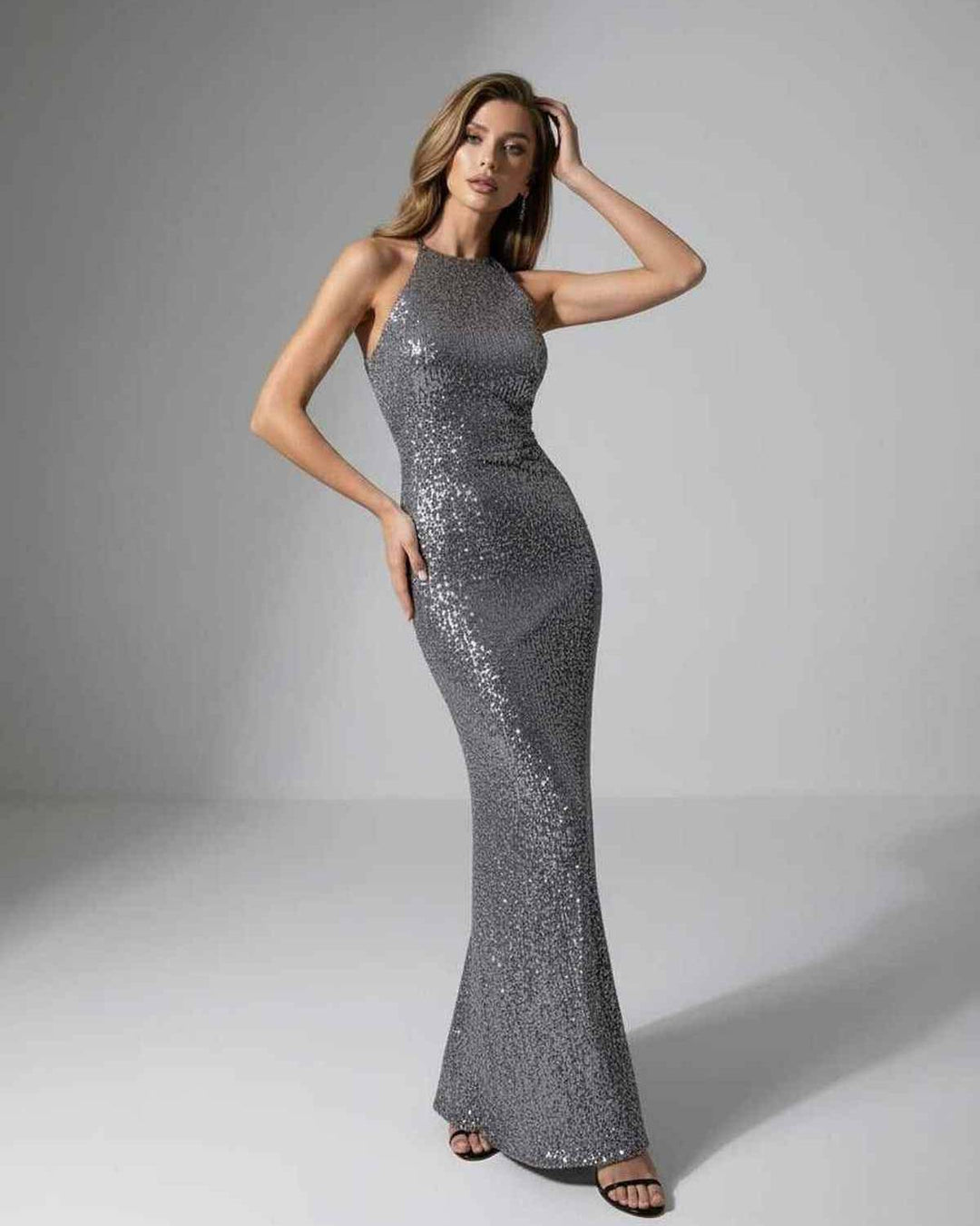 Maxi vestido brillante de mujer con lentejuelas plateadas, cuello halter y silueta ajustada para noche.