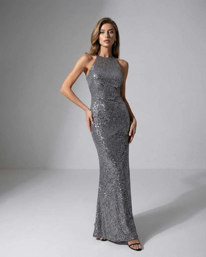 Vestido maxi de lentejuelas plateadas para mujer con cuello halter, ideal para fiesta o noche elegante.