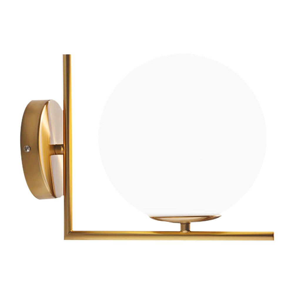 Aplique de pared con elegante globo de vidrio blanco y base de latón dorado. Estilo Mid-Century, luz interior cálida.