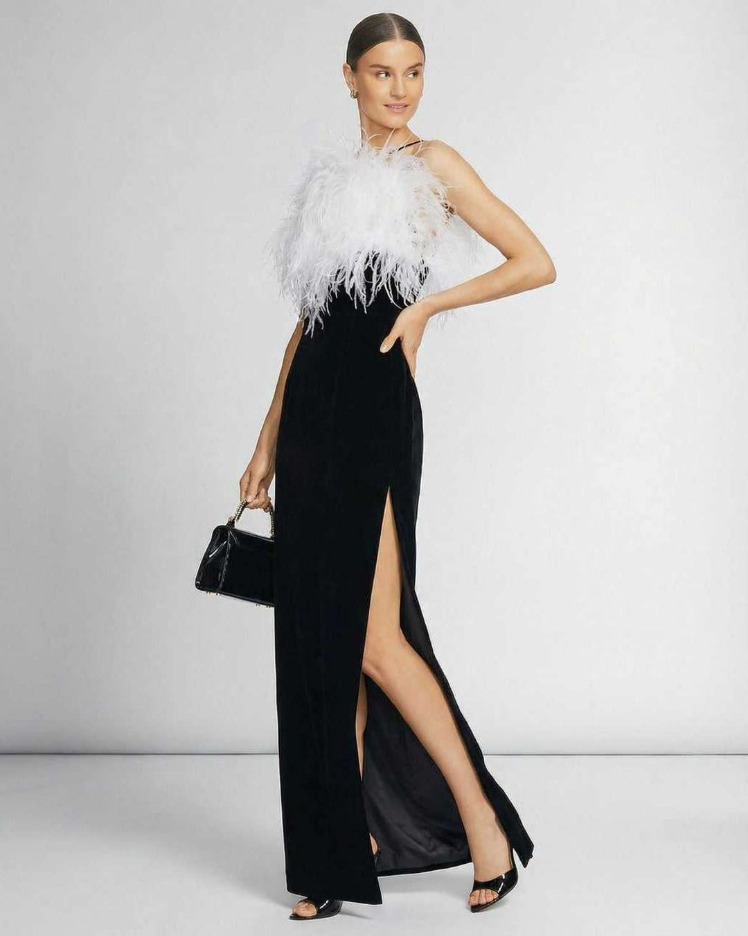 Vestido maxi celeste de noche con espalda abierta y cuello halter. Plumas decorativas para un look elegante.