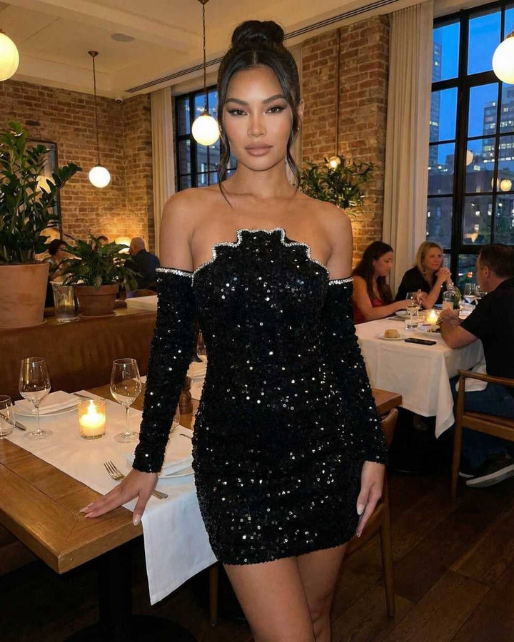 Mujer luciendo vestido mini celeste brillante, ajustado, con mangas largas y escote asimétrico para fiesta.